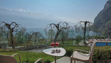 Una terraza con mesa y sillas, con vistas a un paisaje montañoso y una masa de agua.