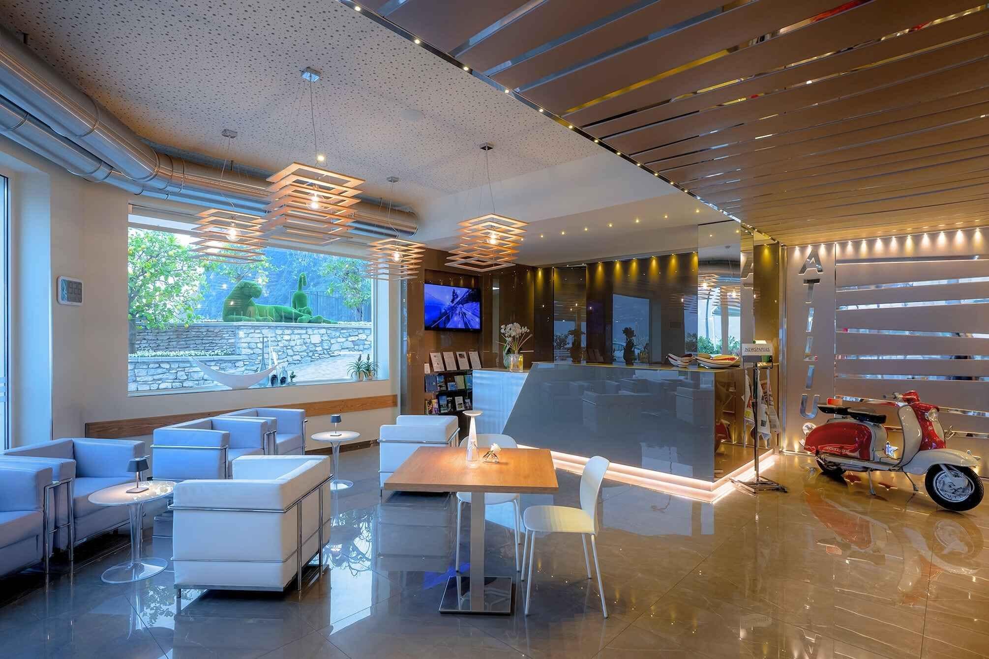 Eine moderne Hotelhalle mit Sitzgelegenheiten, einer Rezeption und einem Fernsehbildschirm.