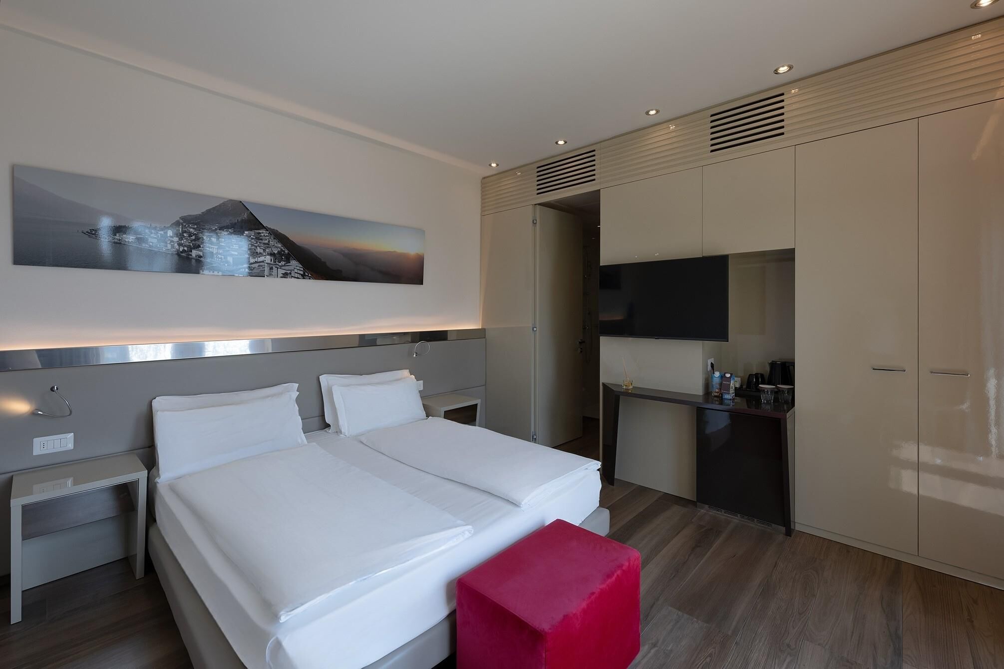 Una habitación de hotel moderna con una cama, mesitas de noche, televisión y armario.