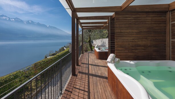 A wooden deck with a hot tub and a view of a lake and mountains. - Hotel Atilius Adults Only (Limone sul Garda)