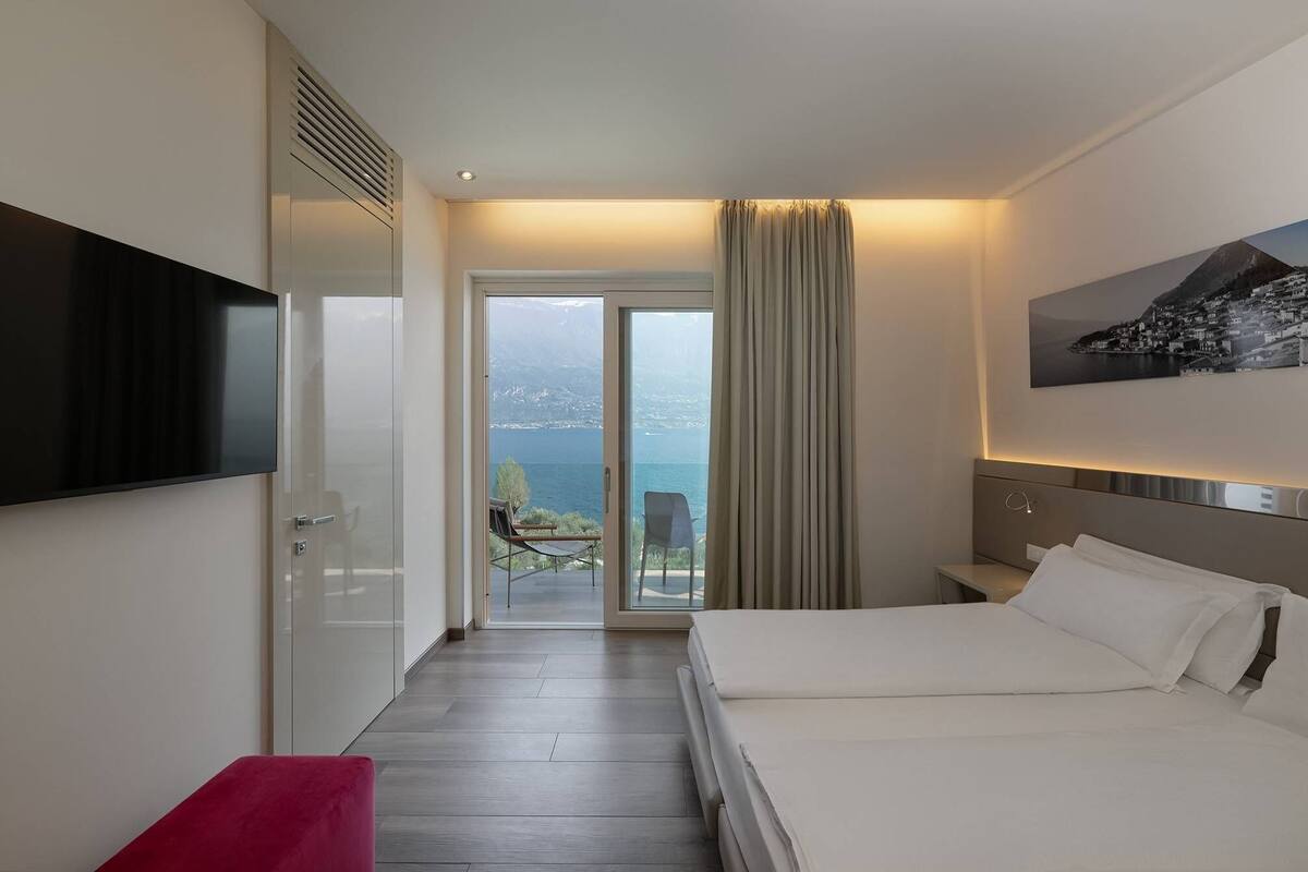 Ein Hotelzimmer mit Bett, Fernseher, Schreibtisch und Meerblick.