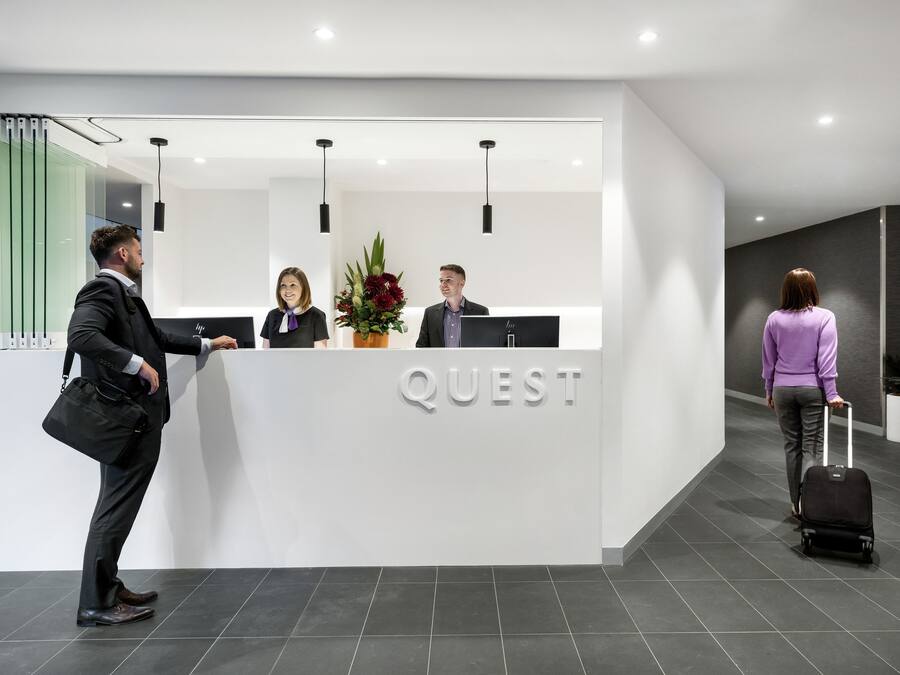 Een modern receptiebalie met het woord "QUEST" duidelijk in het zicht.
