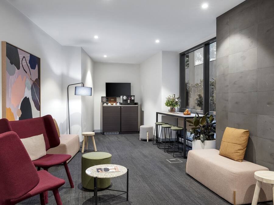 Una sala de estar moderna con un sofá, sillas, una mesa de centro y una cocina al fondo.