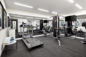 Un gimnasio moderno con cintas de correr, máquinas de pesas y un espejo grande.