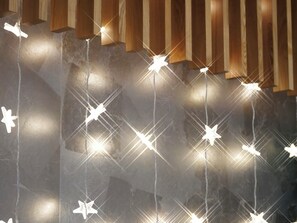 Un escalier avec des rampes en bois et des luminaires en forme d’étoile suspendus.