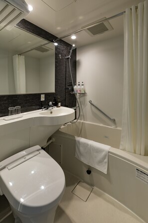 Une salle de bain moderne avec un lavabo blanc, des toilettes, une douche avec une porte en verre et un miroir au-dessus du lavabo.