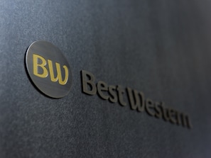 En logotyp med bokstäverna ”BW” och orden ”Best Western” på en strukturerad yta.