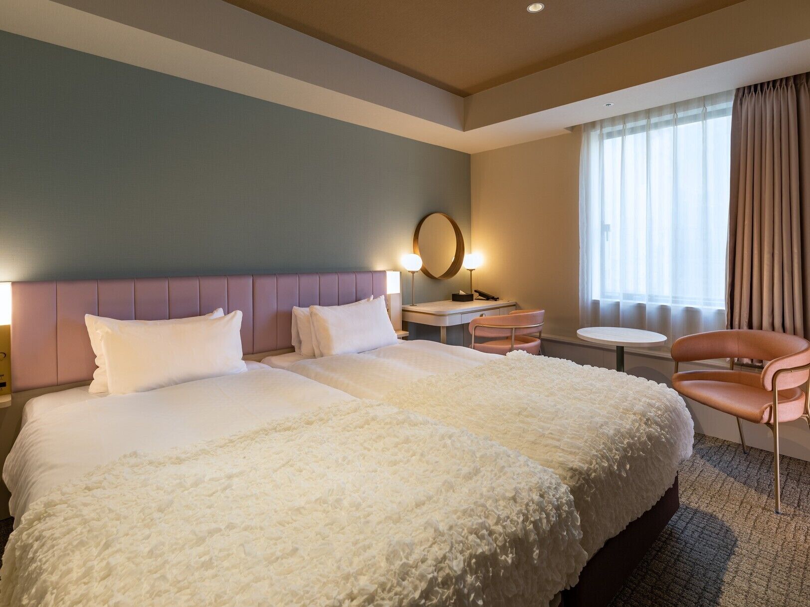 Habitación de hotel con una cama grande, una mesita de noche, una silla, un escritorio y una ventana con cortinas.