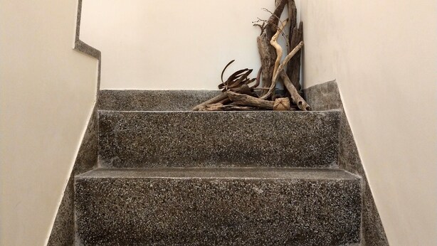 Una escalera con una escultura de madera natural en la parte superior.