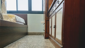 Una habitación con una cama, un armario de madera y suelo de terrazo.