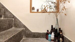 Una escalera con un pequeño ventanal y un jarrón con ramas secas.