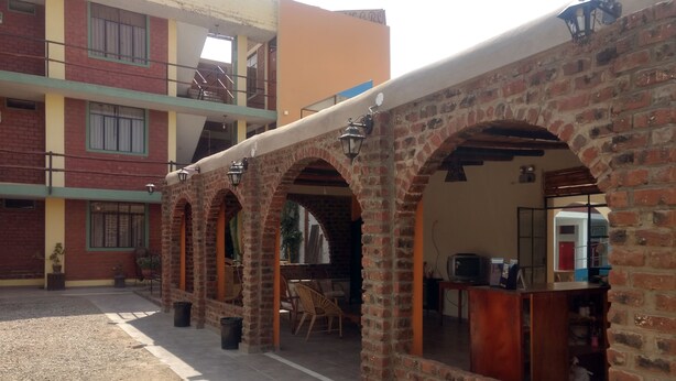 Un patio con arcos de ladrillo, una zona de comedor y un edificio de varios pisos con balcones.
