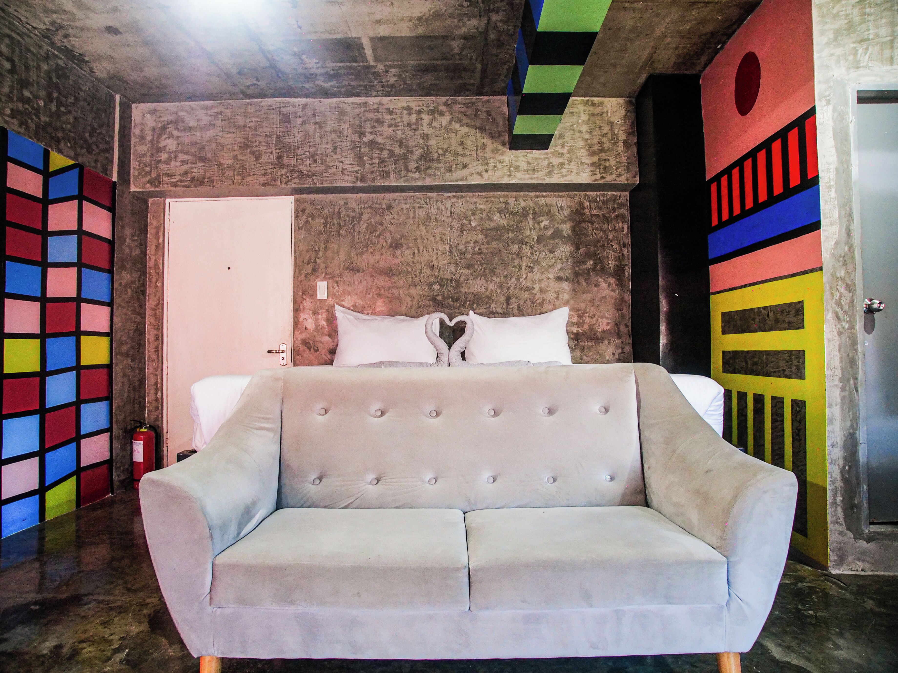 A room with a bed, a sofa, and a door.