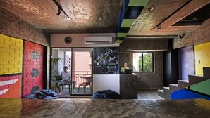 A modern interior with a brick wall, a clock, and a window overlooking a building. - D522 Hostel at Kiener Hills - Near Cebu Airport (Lapu-Lapu)