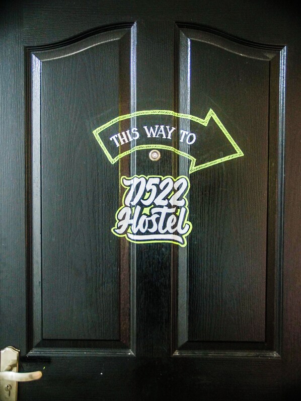 Una puerta con un letrero de neón que indica las indicaciones para un albergue.