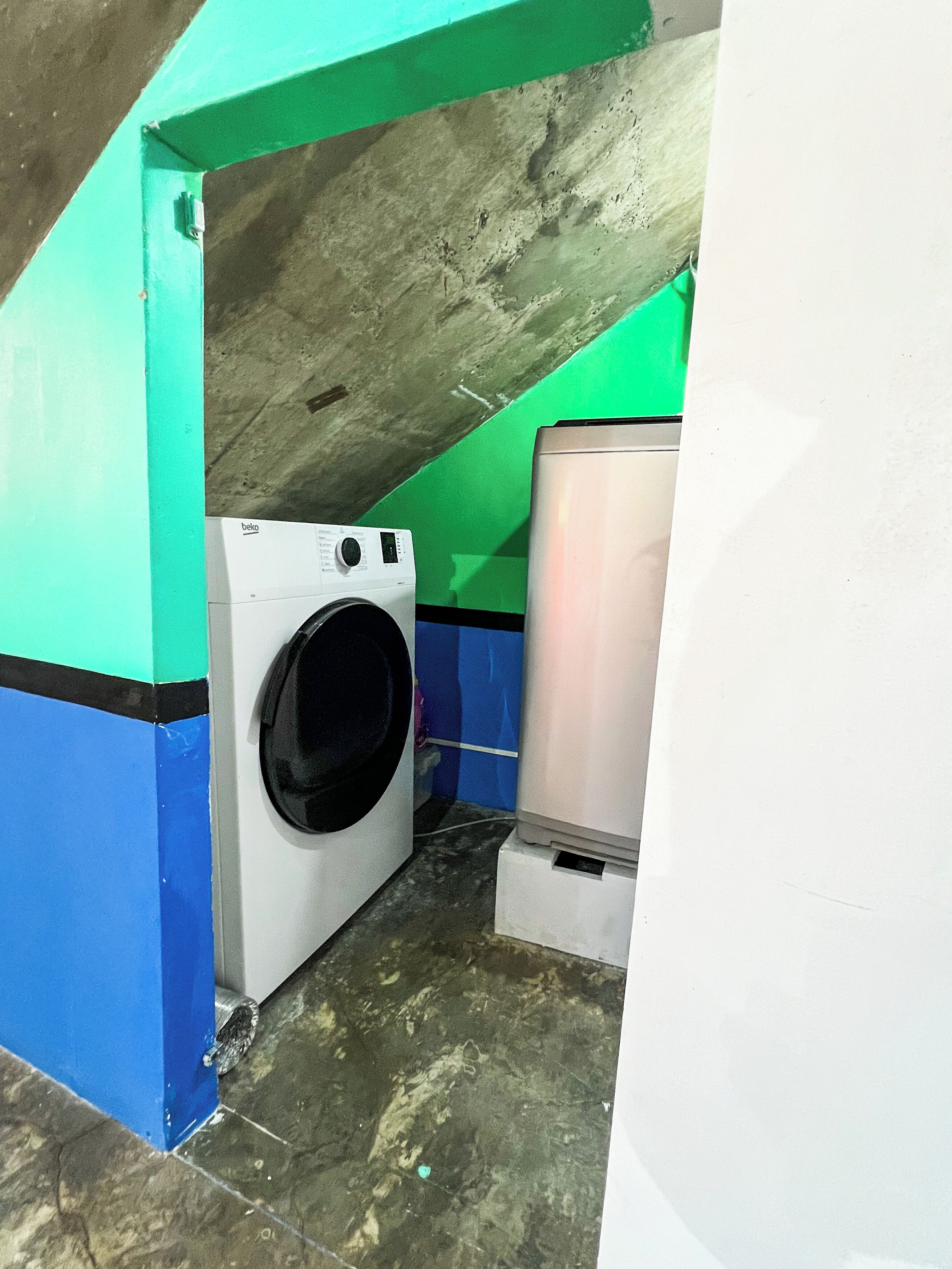 A small laundry room with a washing machine, a dryer, and a metal container.
