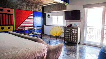 Un dormitorio con una cama, un escritorio, una silla y un televisor.