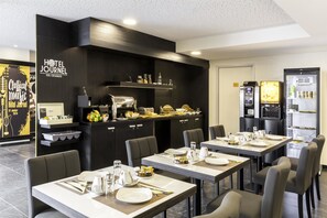 A hotel dining area with tables set for meals, a kitchen area with a refrigerator and microwave, and a minibar. - Best Western Hotel Journel Paris Sud (Ris Orangis)