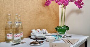 A table with bottles, plates, cups, and a vase of flowers. - Best Western Hotel Journel Paris Sud (Ris Orangis)