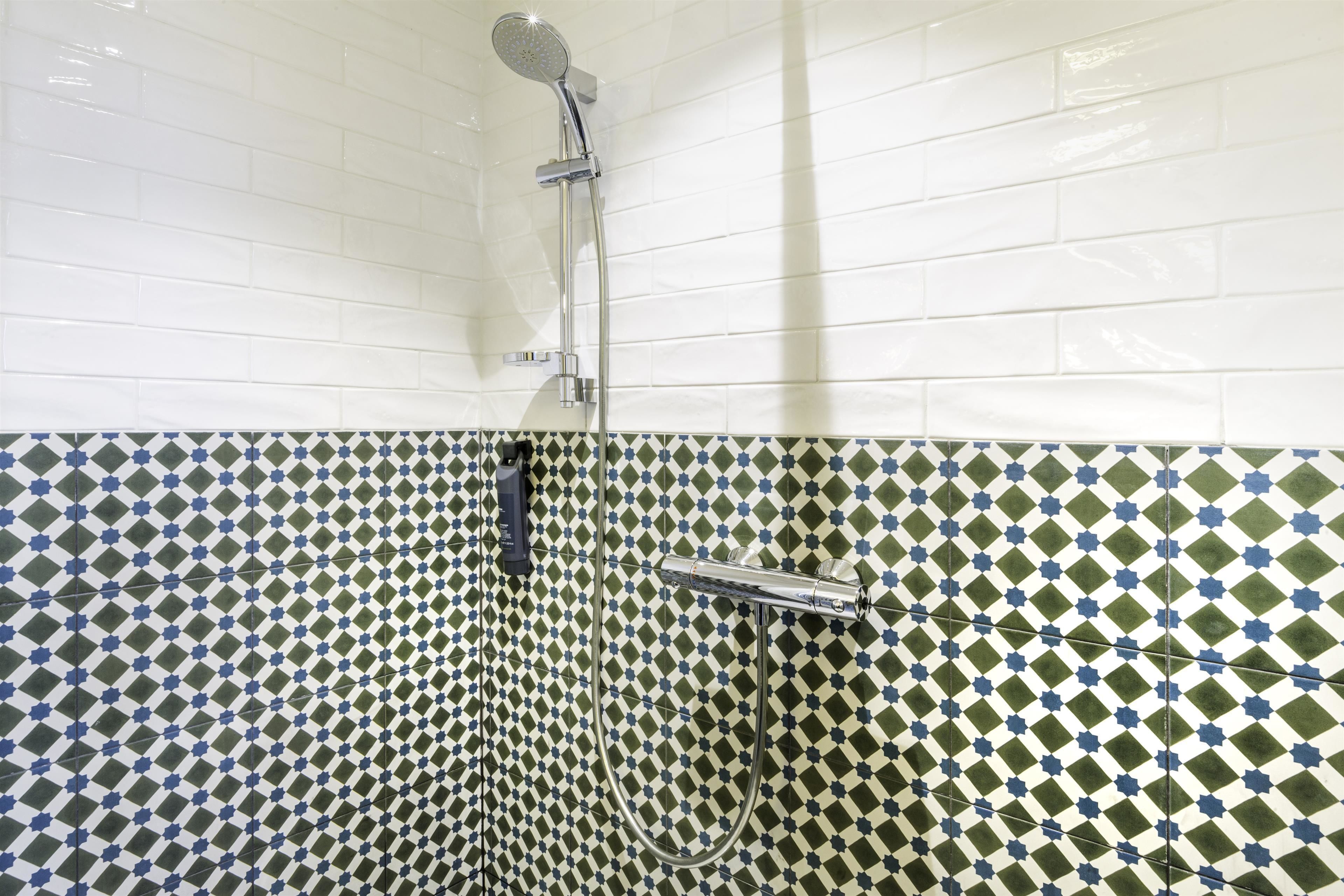 A shower with a handheld showerhead and a wall-mounted faucet.
