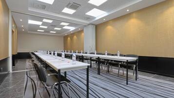 A conference room with long tables, chairs, water bottles, and a whiteboard.