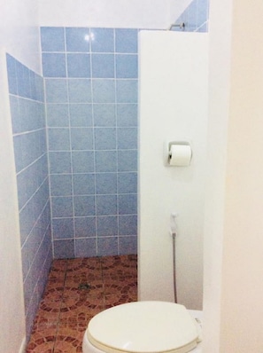 A small bathroom with blue tiles, a white toilet, and a paper towel dispenser.