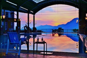 Una terraza con vistas a montañas y una piscina. Hay sillas y una mesa con botellas.