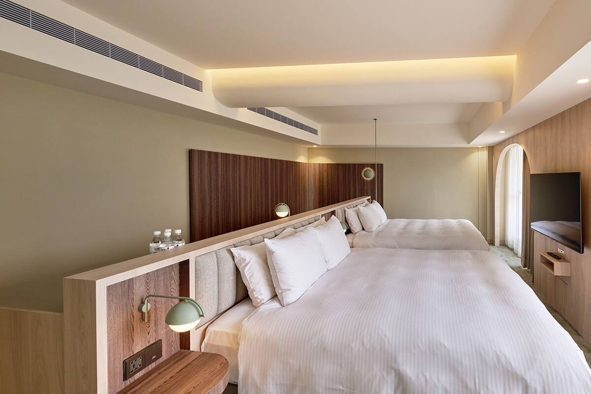 A modern hotel room with a large bed, a TV, and a wooden headboard.