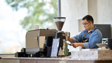 A person operating a coffee machine at a counter with a menu display.