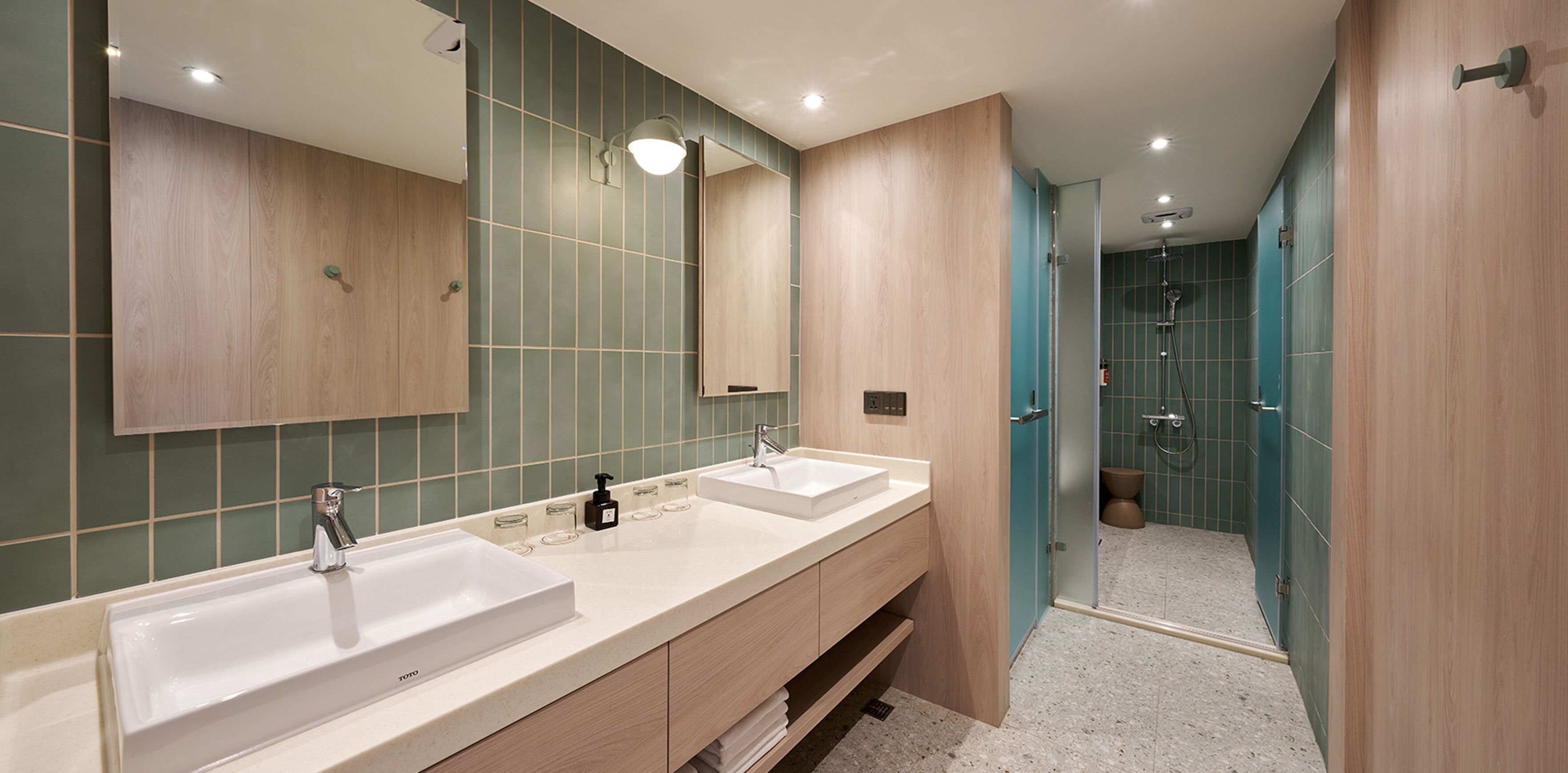 A modern bathroom with two sinks, a large mirror, and a shower area.
