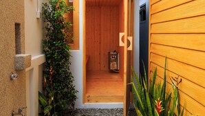 A small wooden sauna with a door, a stone wall, and a concrete path leading to it. - Gala Villa Pattaya (Pattaya)