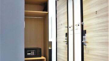 A modern hotel room with a wooden wardrobe, a built-in microwave, and a large mirror.