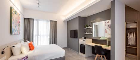 Una habitación de hotel moderna con cama, escritorio y armario.