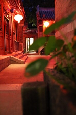 Un patio tradicional con escalones de piedra que conducen a una puerta de madera, iluminado con una luz cálida.