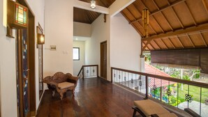A spacious balcony with wooden flooring, a cushioned bench, and a railing. - Baliana Villa Batu Belig (Seminyak)