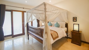 A four-poster canopy bed with a wooden frame and white bedspread, a nightstand with a framed picture, and a sliding glass door leading to a balcony. - Baliana Villa Batu Belig (Seminyak)