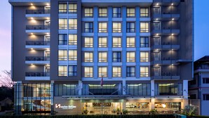 A modern hotel with a prominent 'Swiss-bellinn' sign, multiple balconies, and a well-lit entrance area.