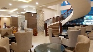 A modern lobby with a curved staircase, comfortable seating, and a decorative wall.