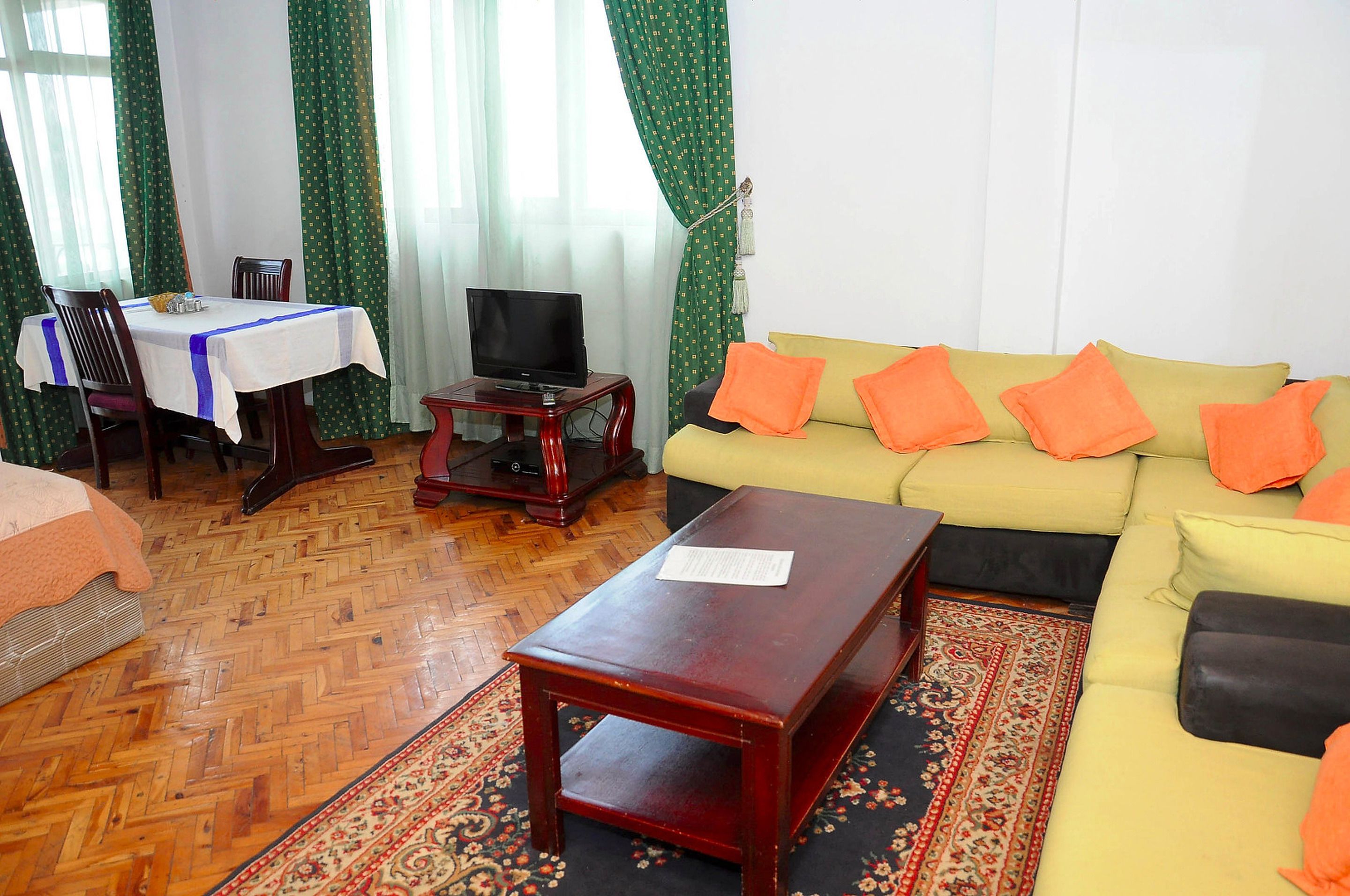 A living room with a sofa, a coffee table, a TV, and a dining area with a table and chairs.