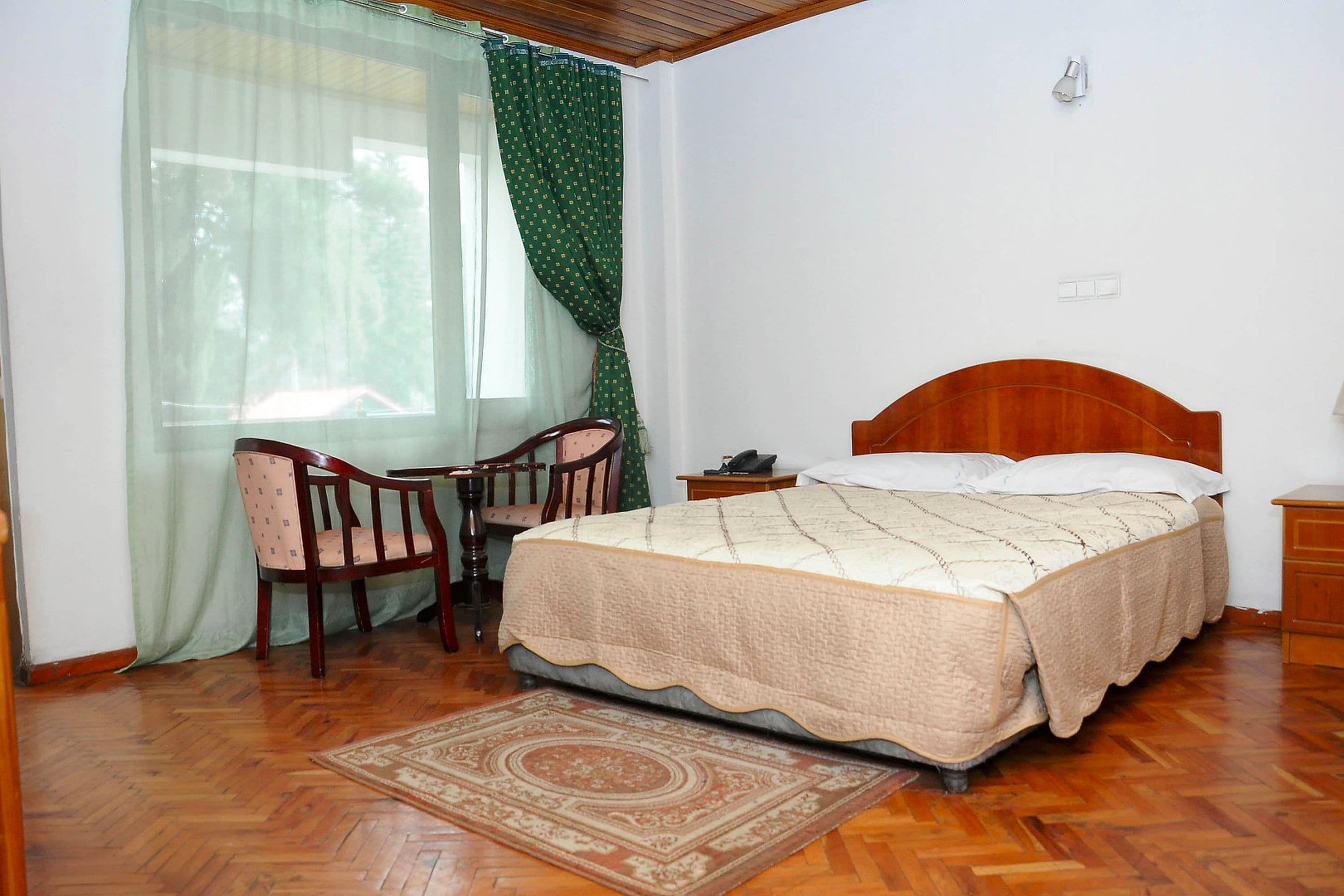 A bedroom with a wooden bed, a desk, and a chair.