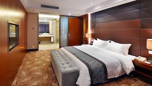 Una habitación de hotel con una cama grande, un banco, una mesita de noche con lámpara y un espejo.