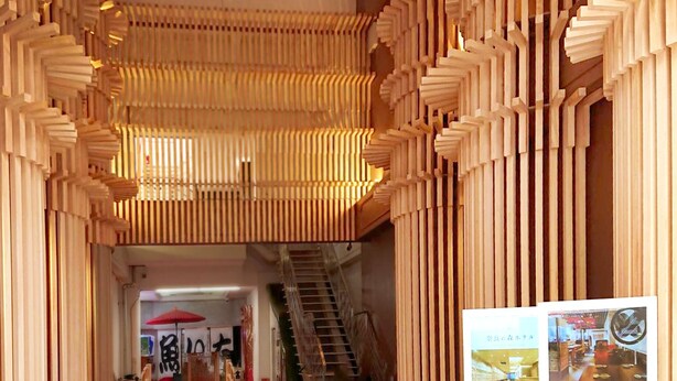 A corridor with wooden slats on the walls and ceiling, a staircase, and a red umbrella in the background. - Narano Mori Hotel (Nara)