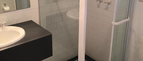 A bathroom with a glass-enclosed shower, a sink, and a toilet.