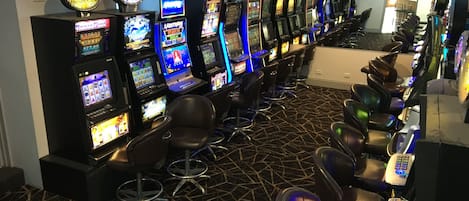 A row of slot machines in a casino with bar stools in front.