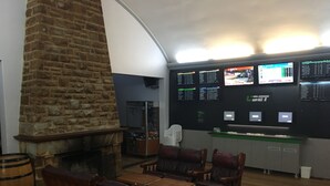 Um hall com lareira de pedra, mobiliário de madeira e várias telas exibindo informações de voos.