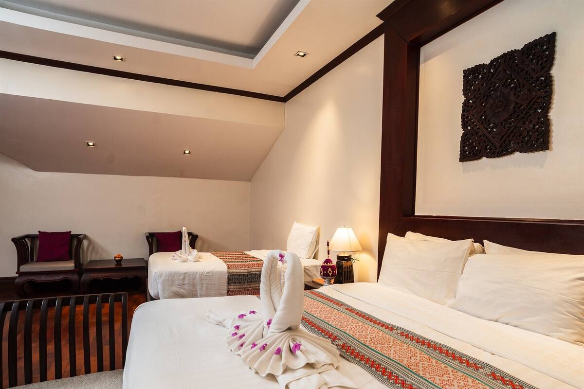A hotel room with two beds, a sitting area with a chair and a table, and a decorative wall piece.