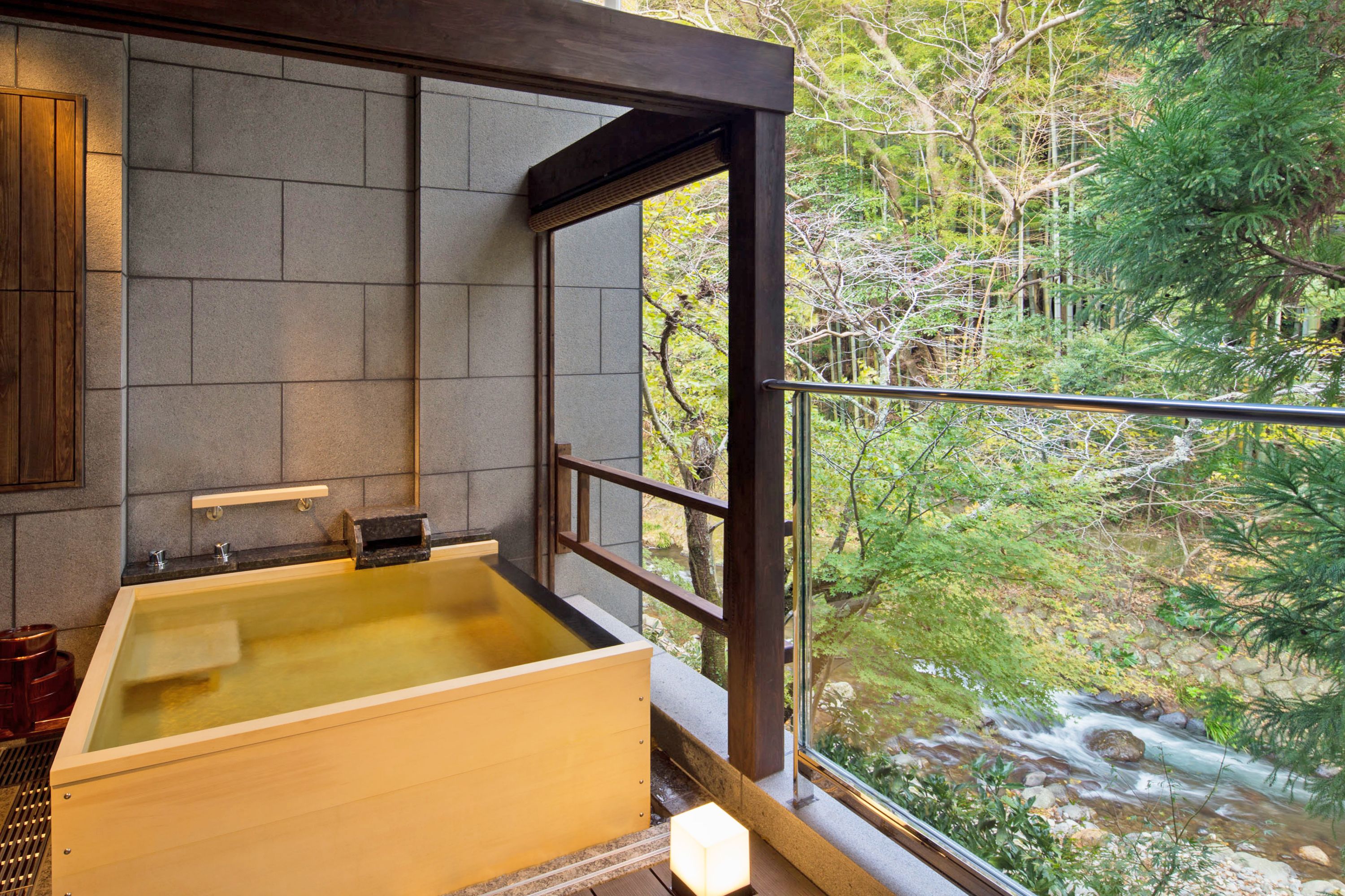 Una bañera de madera con vistas a un arroyo y árboles.