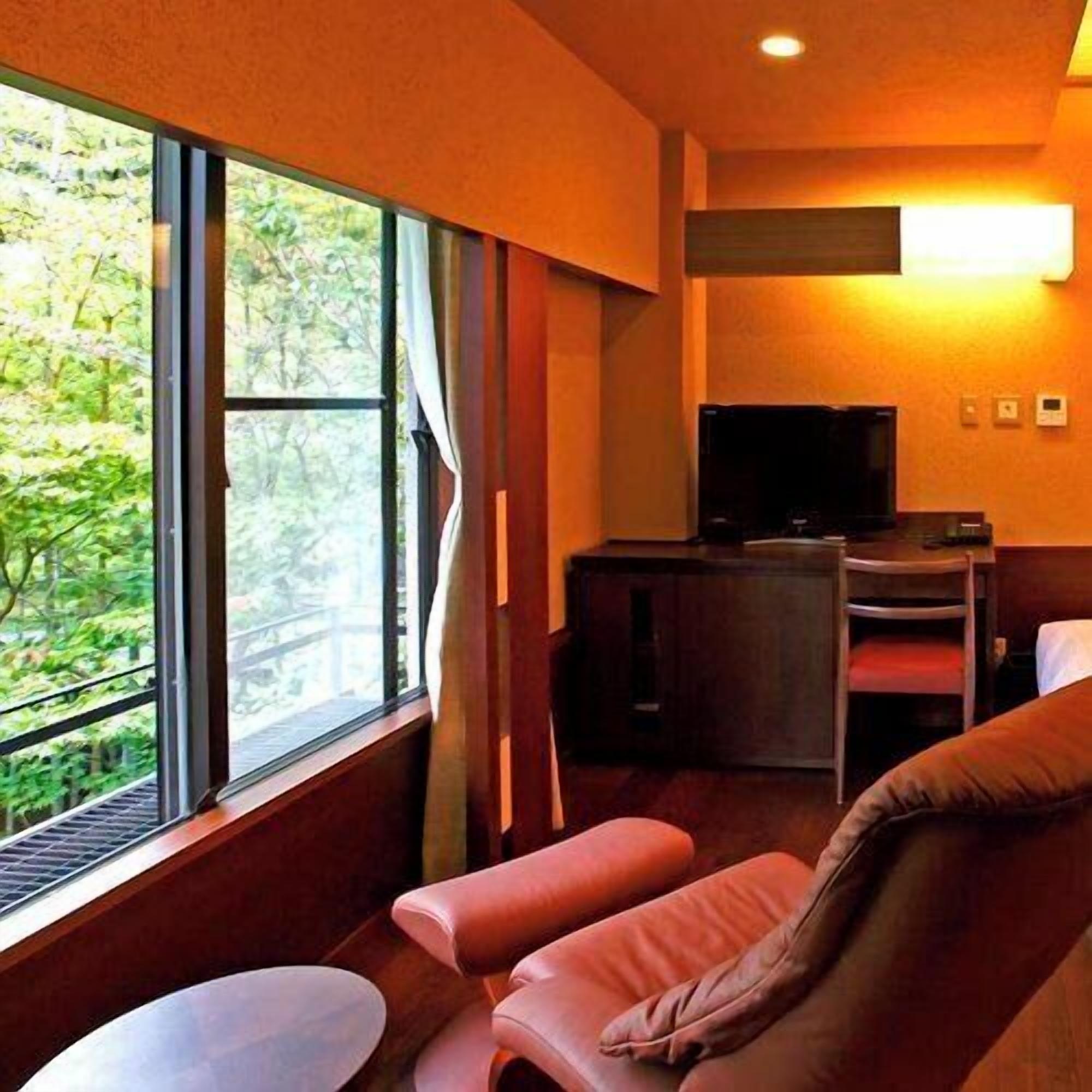 A room with a large window, a television, a desk, and a sofa.