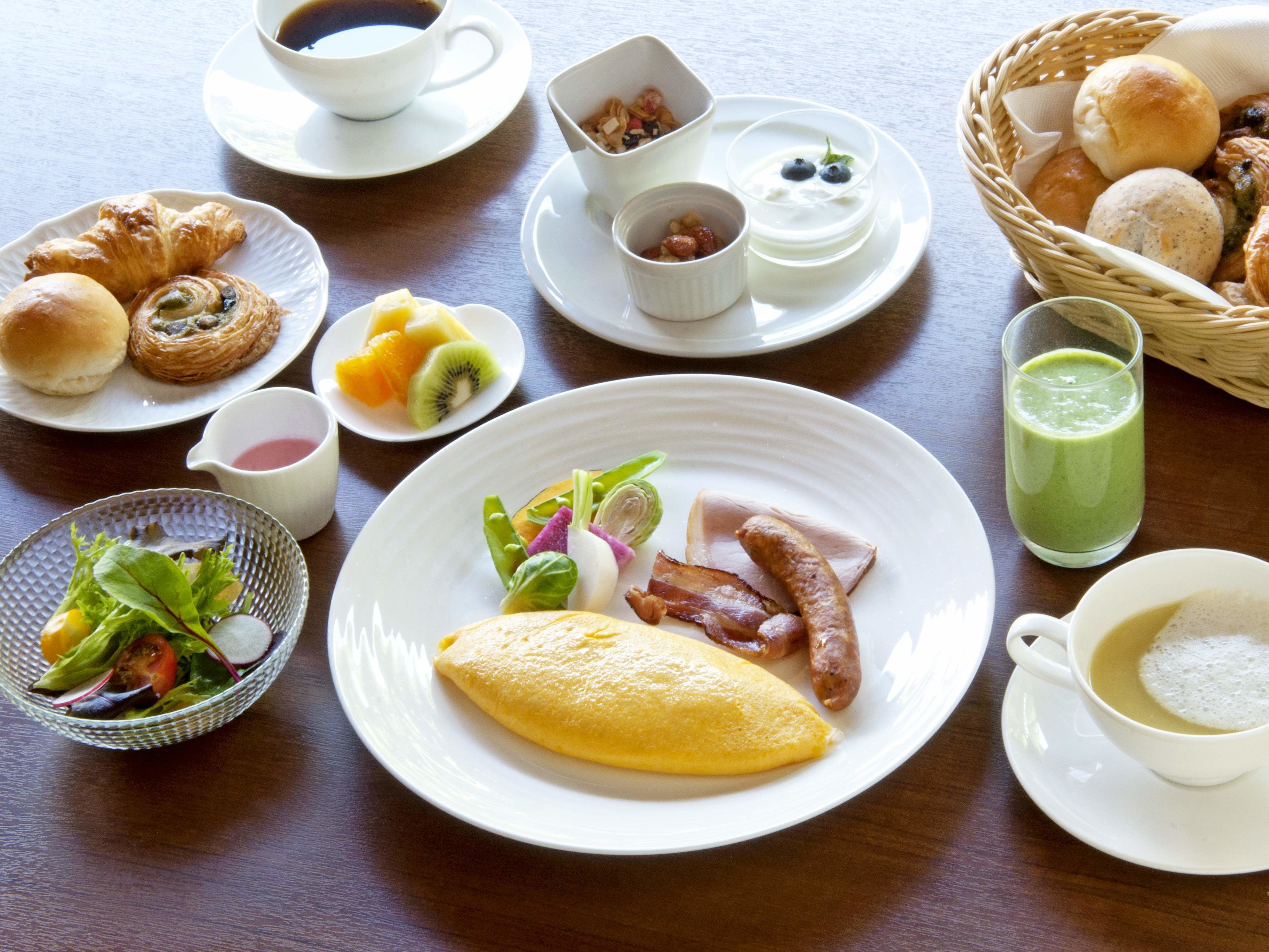 Un desayuno con diferentes platos, como huevos, salchichas y bollería.