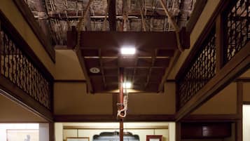 Una habitación tradicional con muebles de madera, una chimenea central y techo de paja.